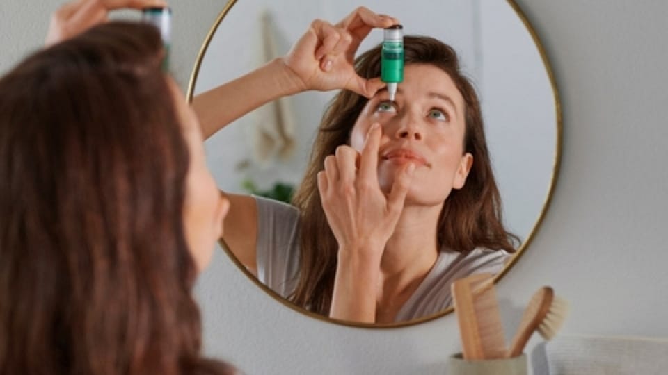 Vrouw die oogdruppels indoet