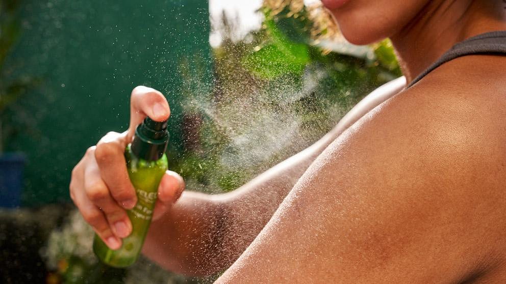 Vrouw sprayt Skin Food Ultra-Light Dry Oil op haar arm