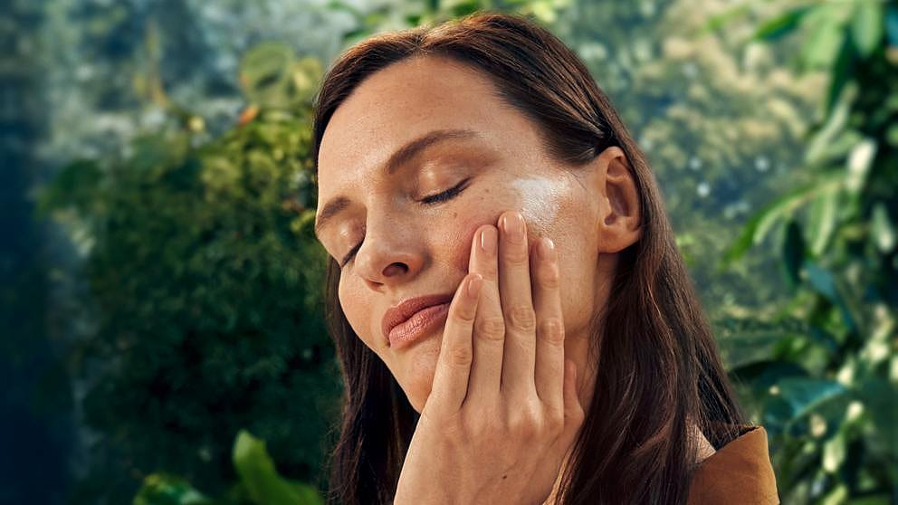 Une femme s'enduit les joues de crème de jour