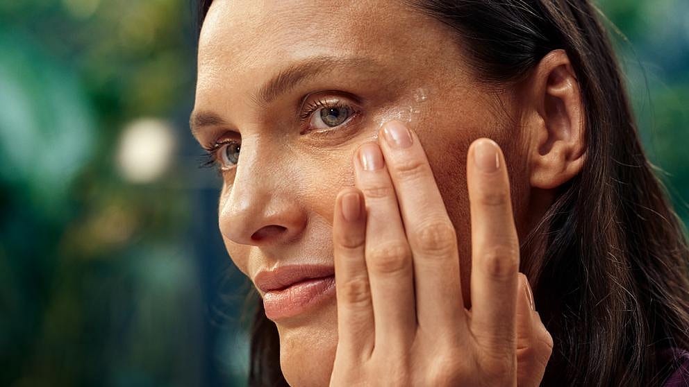 Une femme s'enduit les yeux de crème pour le contour des yeux
