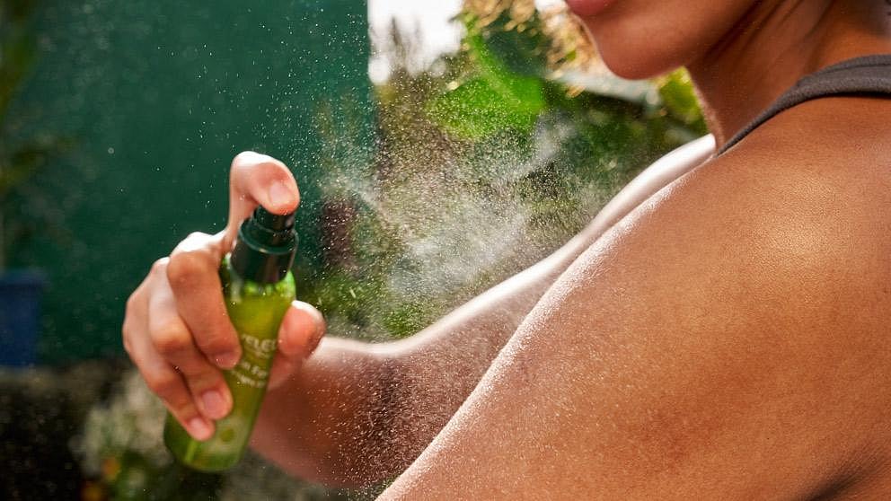 Vrouw sprayt Skin Food Ultra-Light Dry Oil op haar arm