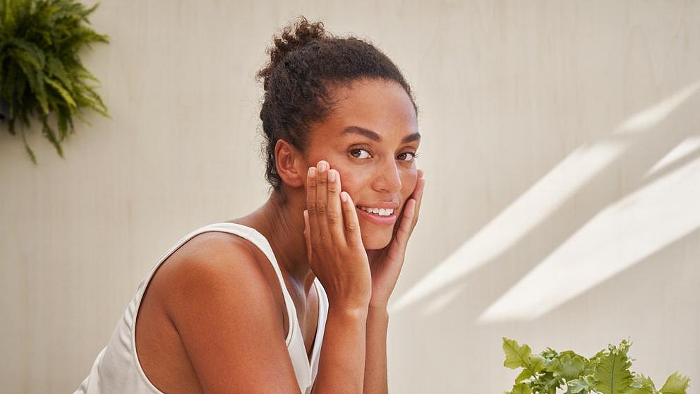 Une femme se nettoie le visage avec le gel nettoyant nourrissant Skin Food
